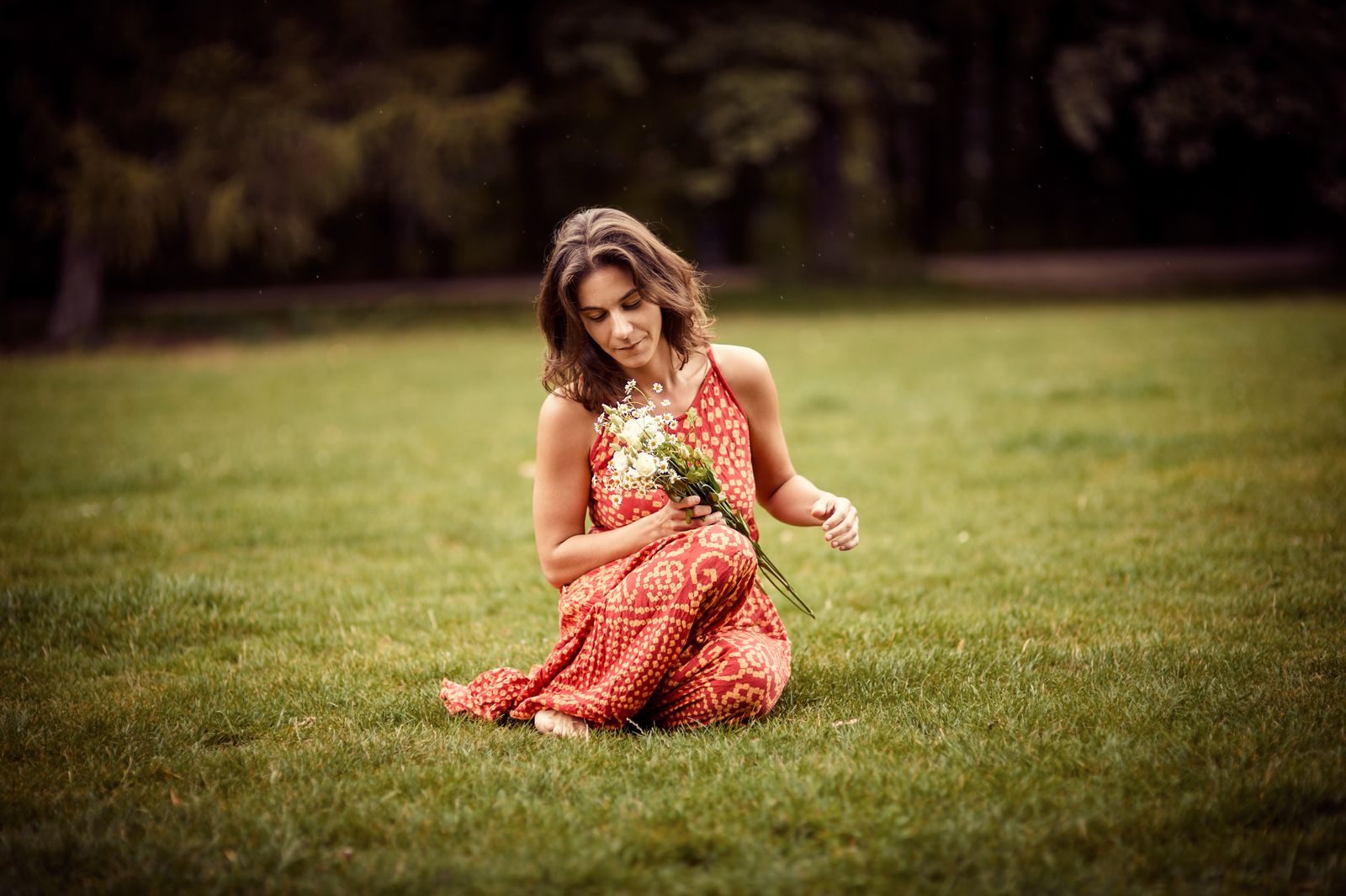 Shila Morelli seduta sul prato con fiori di campo tra le mani